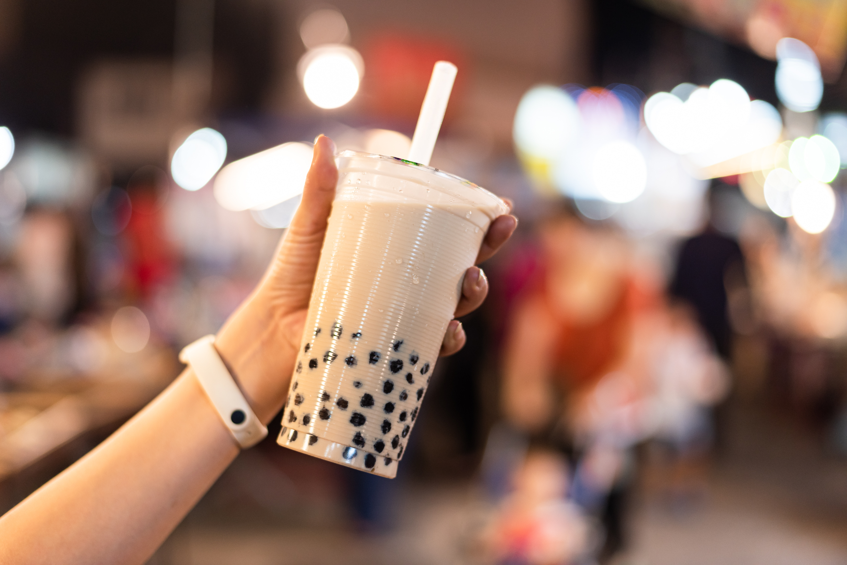 A close-up of a person holding a cup of boba tea.