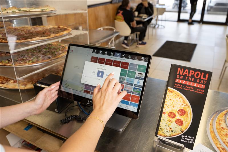 An employee taking an order in a pizza place using LINGA POS.