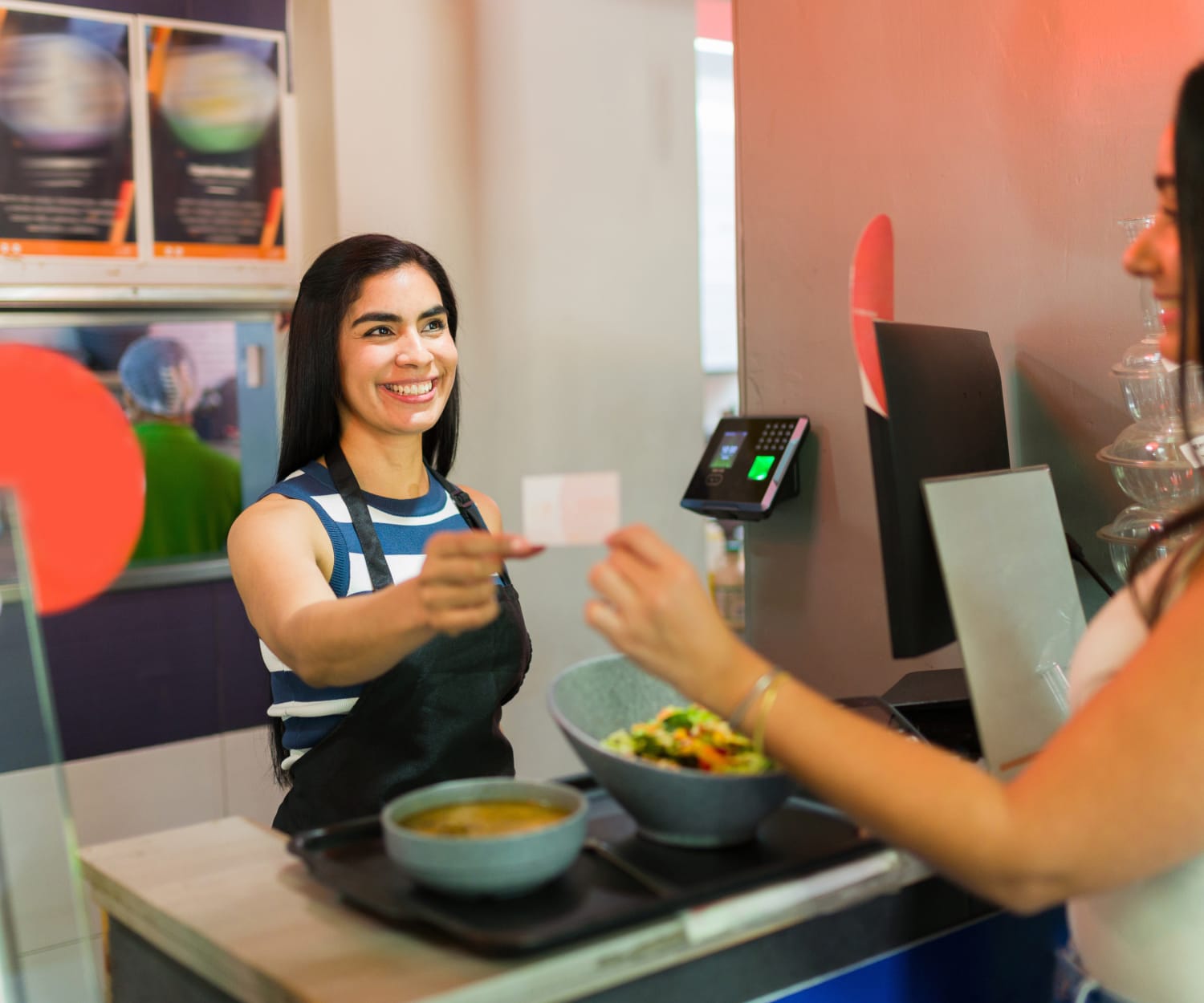 A customer handing a restaurant employee her customer loyalty card to be stamped.
