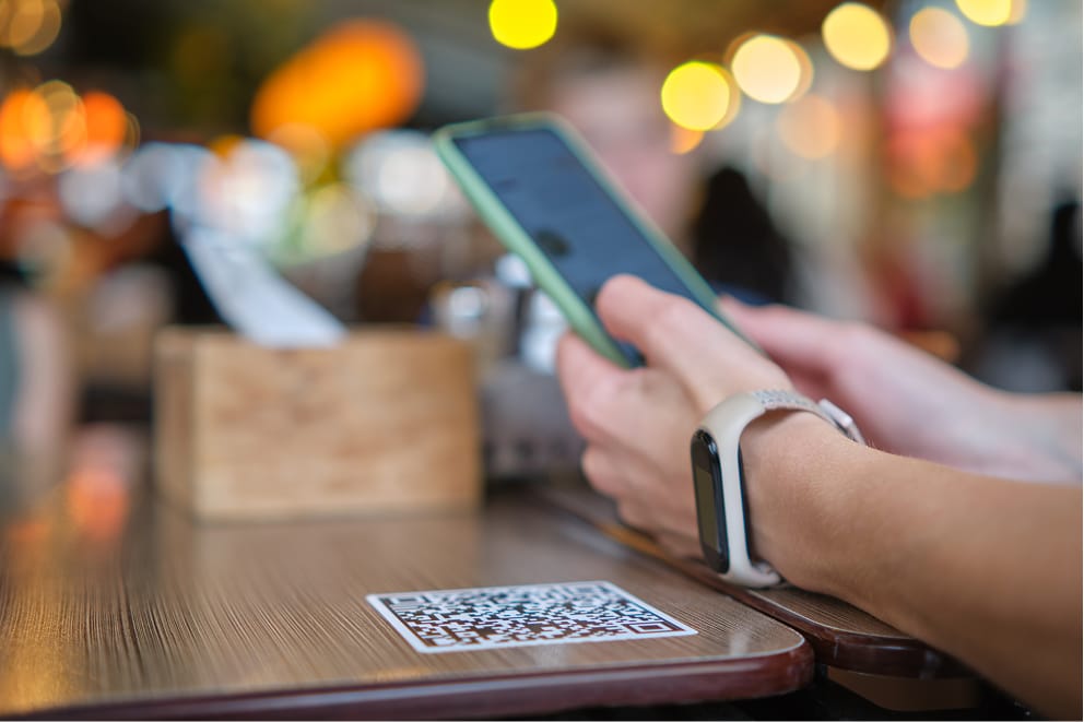 A seated at a café paying for her coffee and pastry using tap on her cell phone.